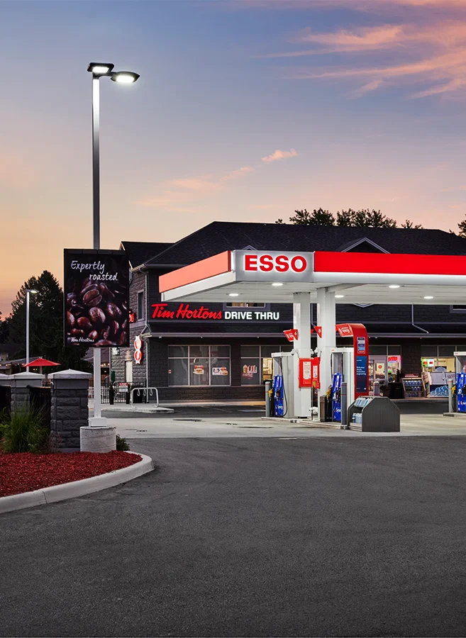 Esso gas station pumps with Tim Hortons and convenient store behind.